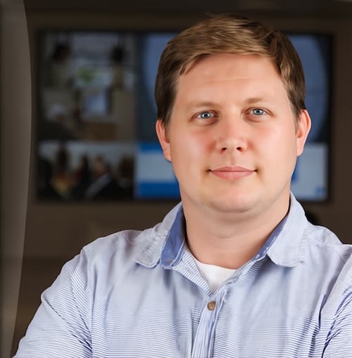 David Fisher, wearing a light blue shirt and seated in an office setting with blurred background.