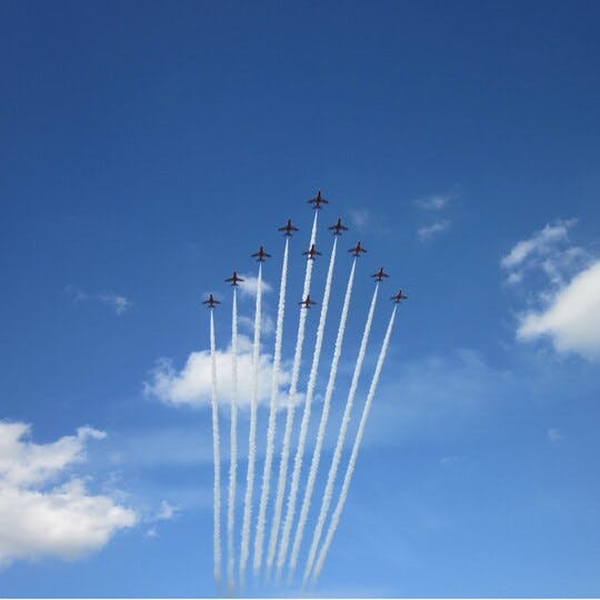 11 jets flying in a v-formation. Blue sky and some clouds in the background.