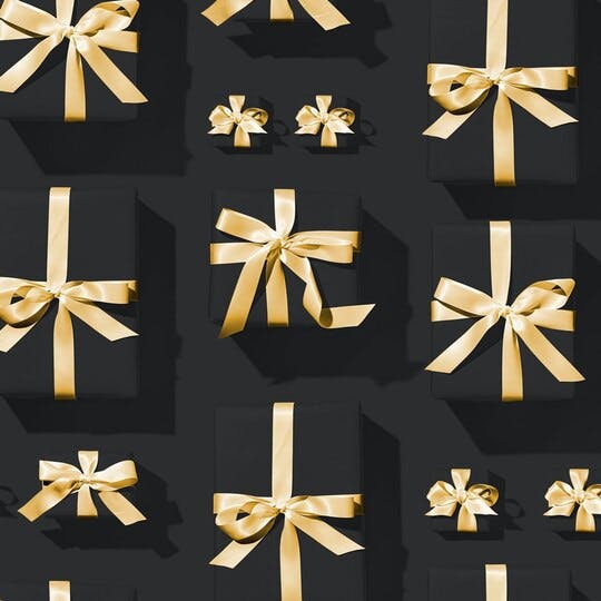Image of different sized black presents on a black background with gold ribbons around each present.