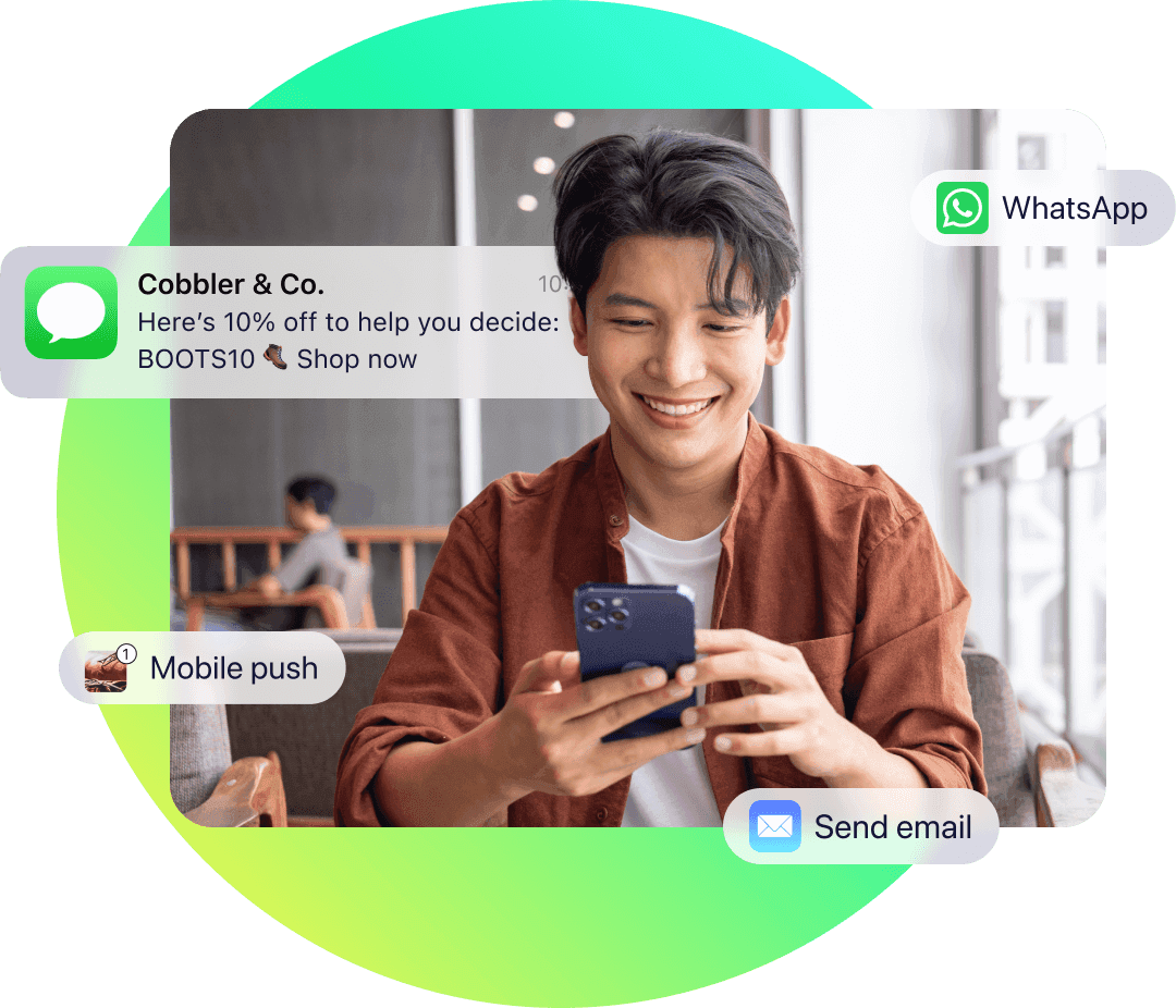 Smiling man viewing promotional SMS message on phone with icons for WhatsApp, mobile push, and email channels.
