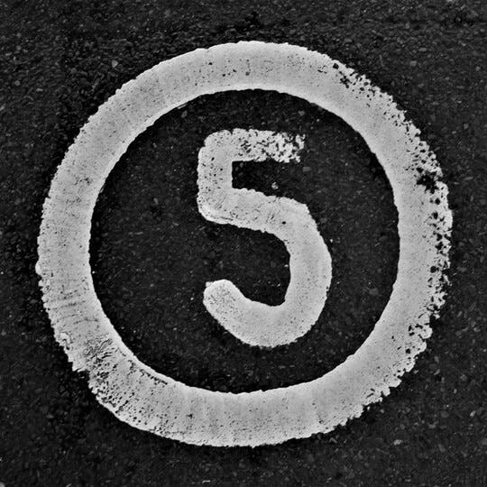 Image of a paved road with the number five and a circle around it painted in white.