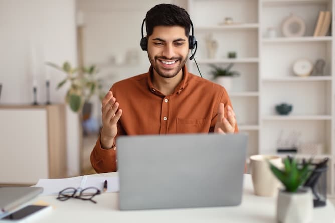 Support specialist wearing a headset smiling at a workstation